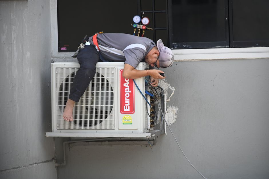 HVAC technician repairing an air conditioner unit